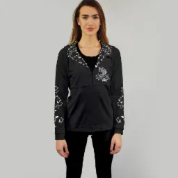 Kobieta w czarnej bluzie z długim rękawem i białym, roślinnym wzorem na kołnierzu, rękawach i klatce piersiowej, pozująca na jednolitym tle.