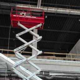 Mal-Nat - Wnętrze w trakcie prac wykończeniowych, widoczny podnośnik nożycowy z pracownikami na tle sufitu i instalacji wentylacyjnej.