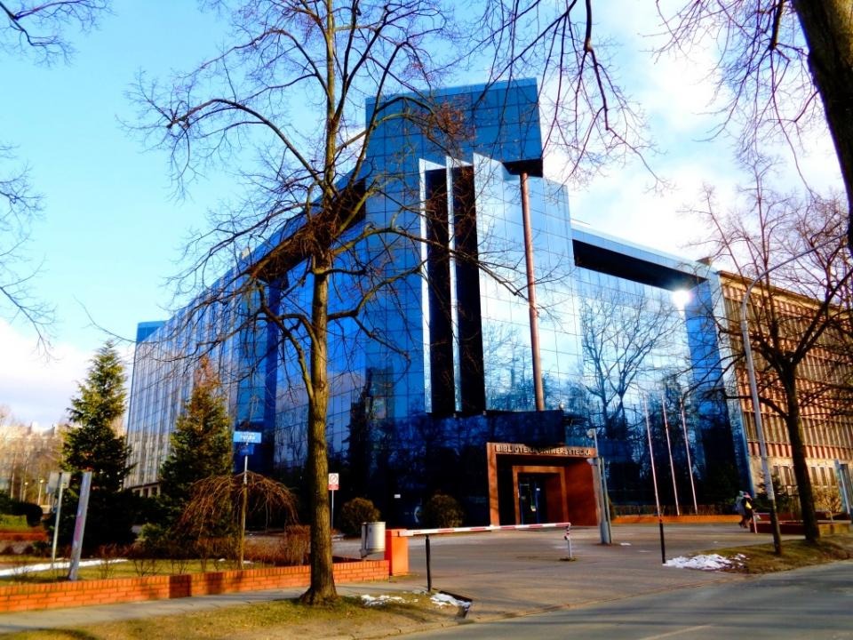 Nowoczesny budynek biurowy z przeszkloną fasadą w Chodzieży, z widocznym otoczeniem miejskim i drzewami bez liści.