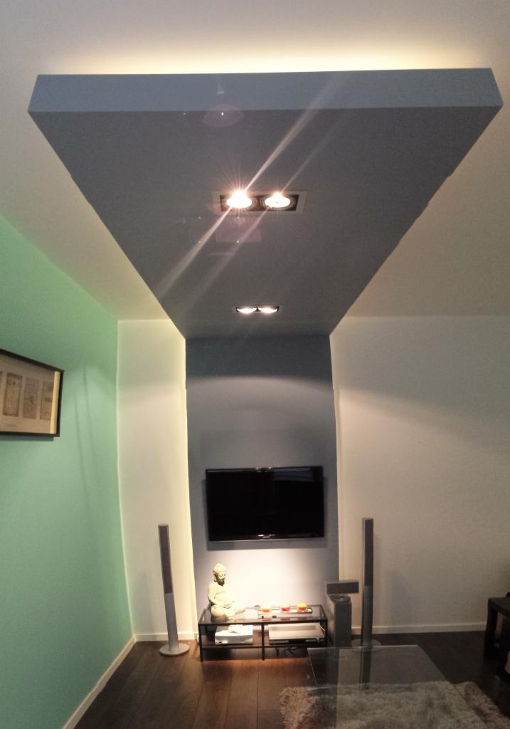 Nowoczesny salon z podwieszanym sufitem w odcieniach szarości, punktowe oświetlenie, minimalistyczny wystrój i elementy dekoracyjne. Widok z dołu.