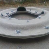 Szara, betonowa obudowa z licznymi śrubami motylkowymi, prawdopodobnie element konstrukcyjny do montażu, leżąca na szarej powierzchni.