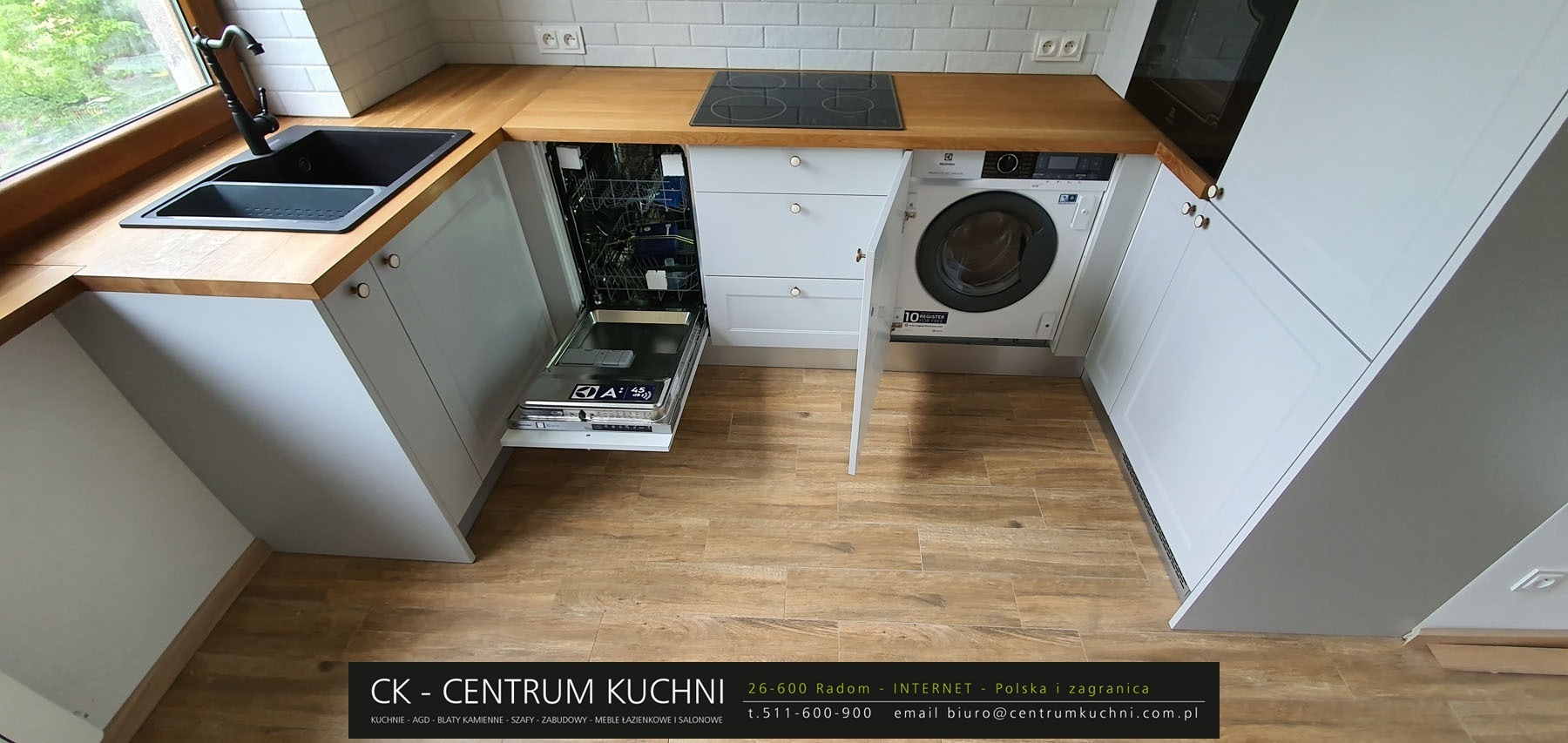 Nowoczesna kuchnia z zabudową w odcieniach szarości, drewniany blat, zintegrowana pralka i otwarta zmywarka, widok z góry.