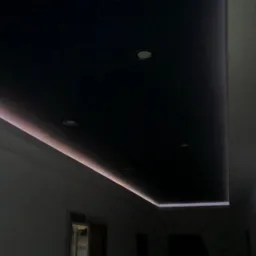 Czarne podwieszane sufity z oświetleniem LED wzdłuż krawędzi, widoczne reflektory punktowe.