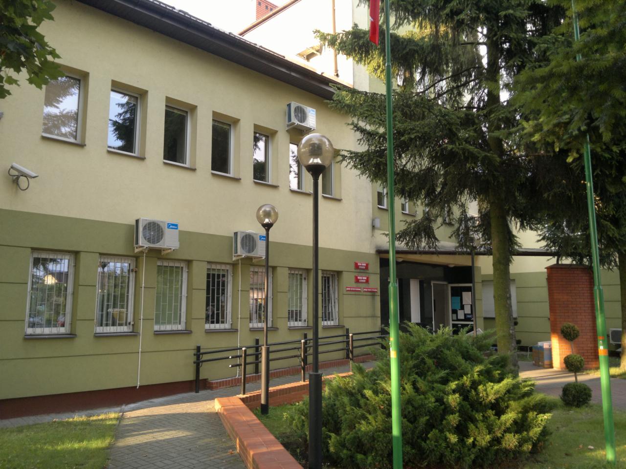 Budynek biurowy z zamontowanymi klimatyzatorami Midea, widok z zewnątrz w Kielcach. Widoczne lampy uliczne i zieleń.