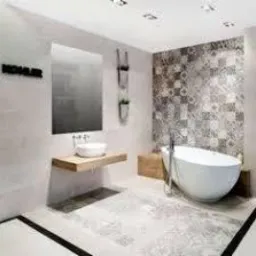 Nowoczesna łazienka z wolnostojącą wanną w kształcie łzy, umywalką nablatową na drewnianym blacie, dużym lustrem, płytkami w geometryczne wzory na ścianie i podłodze oraz czarnym napisem 'KOHLER'...