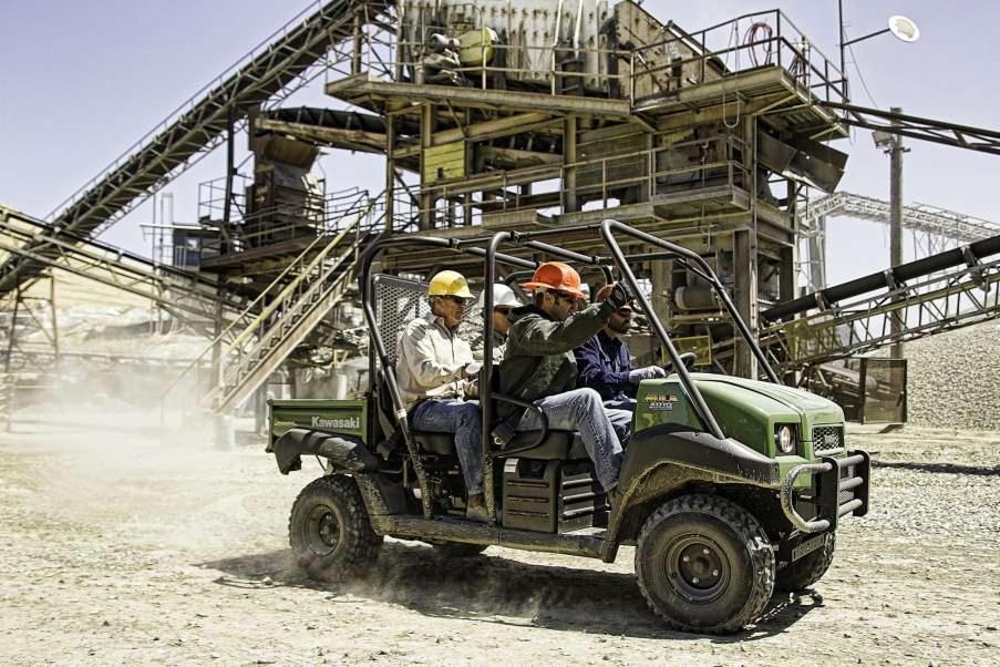 Zielony pojazd Kawasaki MULE 4010 TRANS 4X4 DIESEL z załogą w kaskach na terenie kopalni kruszywa, z widoczną konstrukcją przesiewacza i taśmociągów w tle.