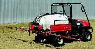 Czerwony pojazd Kawasaki MULE 4010 DIESEL 4X4 z białym zbiornikiem i rozpylaczem, stojący na trawiastym terenie, widok z tyłu pod lekkim kątem.