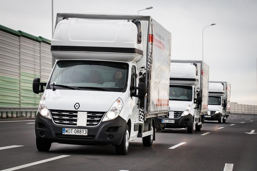 Kaskada białych busów Renault Master z zabudową kontenerową w ruchu na autostradzie, widok z przodu, tablice rejestracyjne WOT 08813.