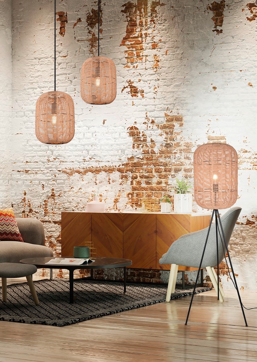 Salon z lampami wiszącymi i podłogową z abażurami z plecionki, ustawionymi na tle ściany z cegły i drewnianej komody. Nowoczesny design oświetlenia.