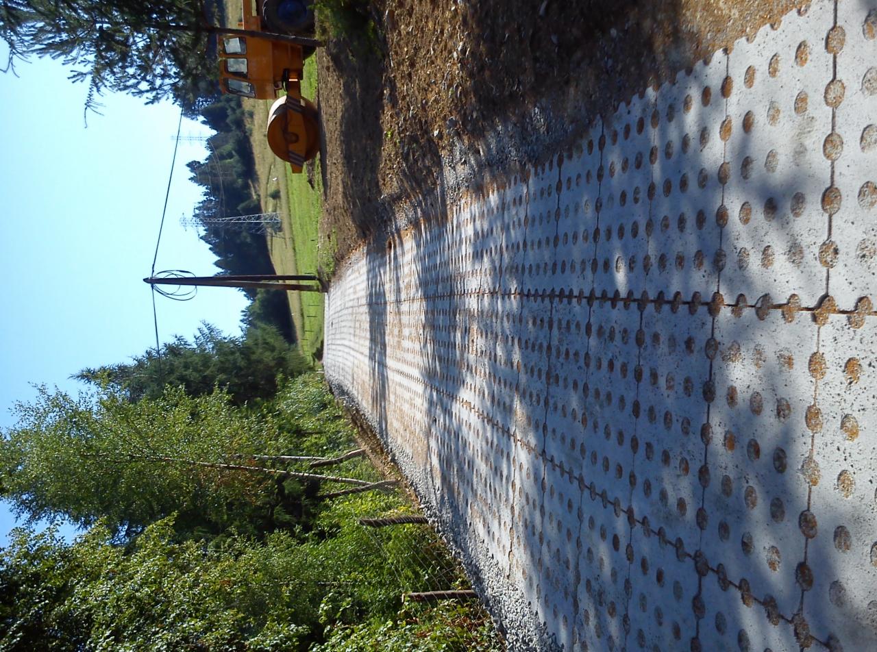 Długa ścieżka z ażurowych płyt betonowych, widok z boku, zieleń w tle, częściowo widoczny walec drogowy i słup energetyczny. Nietypowy wzór kostki z okrągłymi otworami.