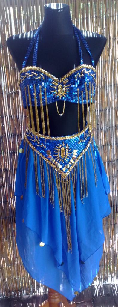 Błękitny, cekinowy strój do tańca brzucha z frędzlami, prezentowany na manekinie na tle bambusowej ściany.