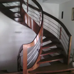 Kręte schody drewniane z metalowymi relingami, widok z dołu, parkiet na podłodze.