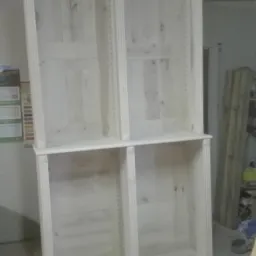 Surowa, drewniana szafa na wymiar z kolumnami dekoracyjnymi, widoczna w warsztacie. Szafa bez wykończenia, z widocznymi otworami na półki.