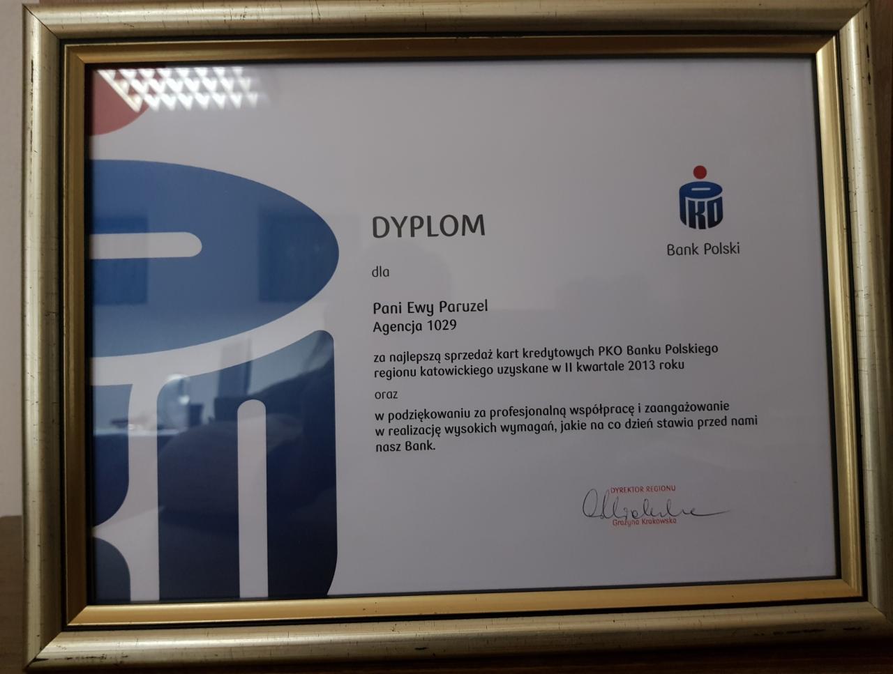 Oprawiony w złotą ramkę dyplom dla Pani Ewy Paruzel z Agencji 1029 za najlepszą sprzedaż kart kredytowych PKO Banku Polskiego w regionie katowickim w II kwartale 2013 roku, z podpisem Dyrektora...