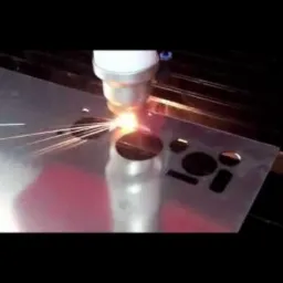 Precyzyjne cięcie laserowe metalu. Iskry i intensywne światło podczas obróbki CNC. Wycinanie otworów o różnych kształtach w metalowej płycie.