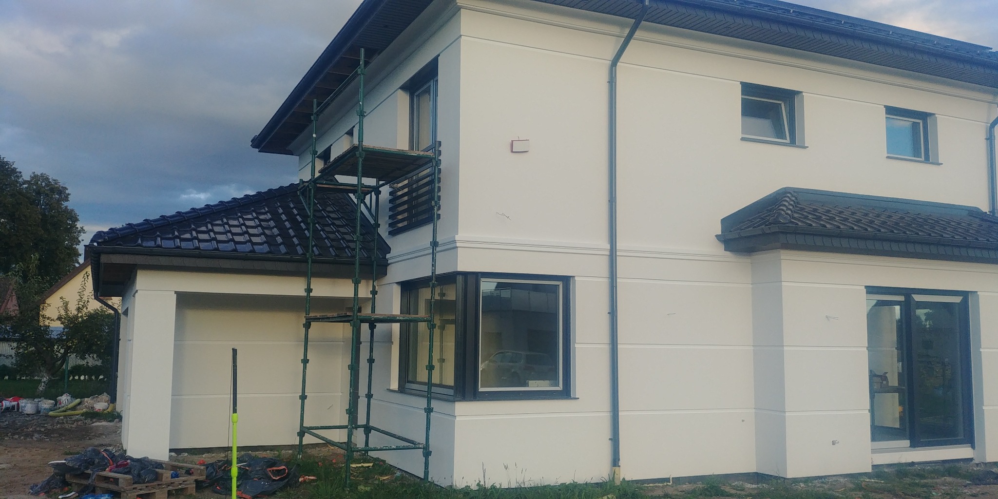 Dom jednorodzinny w Kępice po nałożeniu jasnej elewacji, widoczne rusztowanie i teren przygotowany do dalszych prac.