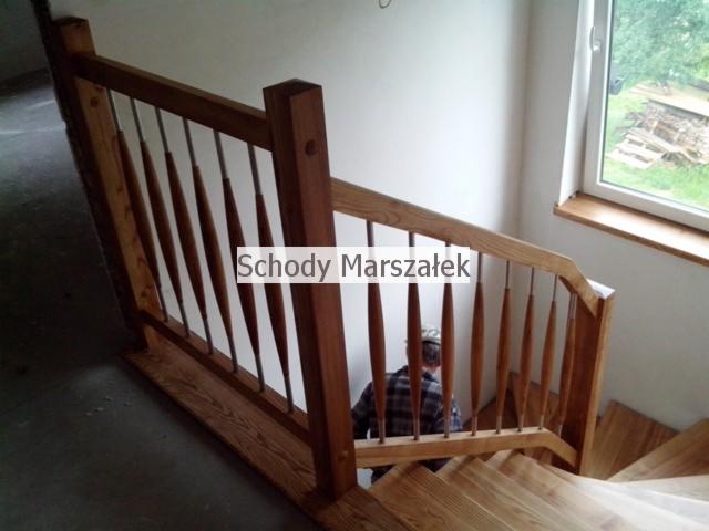 Drewniane schody z balustradą o unikalnym designie szczebli w kształcie wrzecion, widok z góry. Osoba w tle. Naturalne światło z okna.
