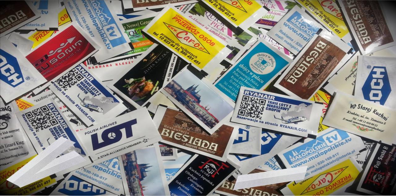 Stos wykałaczek reklamowych z nadrukami logo różnych firm, restauracji i linii lotniczych, ułożonych chaotycznie na płaskiej powierzchni.