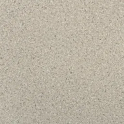 Beżowa wykładzina PCW o drobnej, nieregularnej strukturze z widocznymi ciemniejszymi i jaśniejszymi plamkami, przypominająca naturalny kamień.