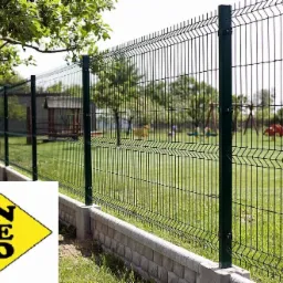 Nowoczesne ogrodzenie panelowe z podmurówką na tle zielonego trawnika i placu zabaw. Solidna konstrukcja, estetyczny wygląd, ochrona posesji.