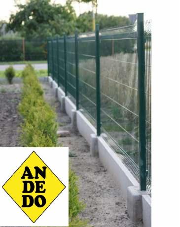 Zielone ogrodzenie panelowe z podmurówką betonową, widok z boku, zieleń w tle. Charakterystyczne słupki i siatka. Element krajobrazu.