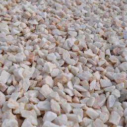 Beżowo-białe kamienie ozdobne, drobny grys marmurowy, idealne do dekoracji ogrodu i ścieżek, równomiernie rozłożone, widok z bliska.