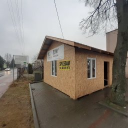 DARBUD Dariusz Zaręba - Niedokończony budynek z drewnianych płyt OSB z oknami PCV, z tablicą reklamową firmy budowlanej i napisem 'Sprzedam', stojący na chodniku obok drzewa i ulicy w pochmurny dzień.