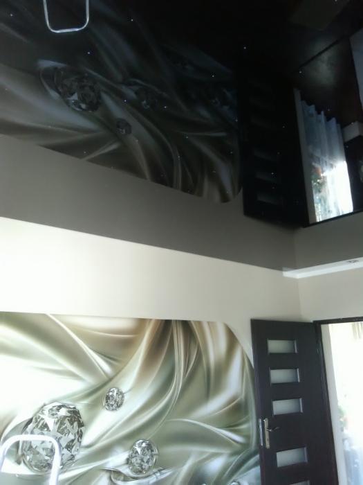 Wnętrze z fototapetą przedstawiającą drapowane tkaniny i diamenty na ścianie i suficie, widoczna część drabiny malarskiej i drzwi.