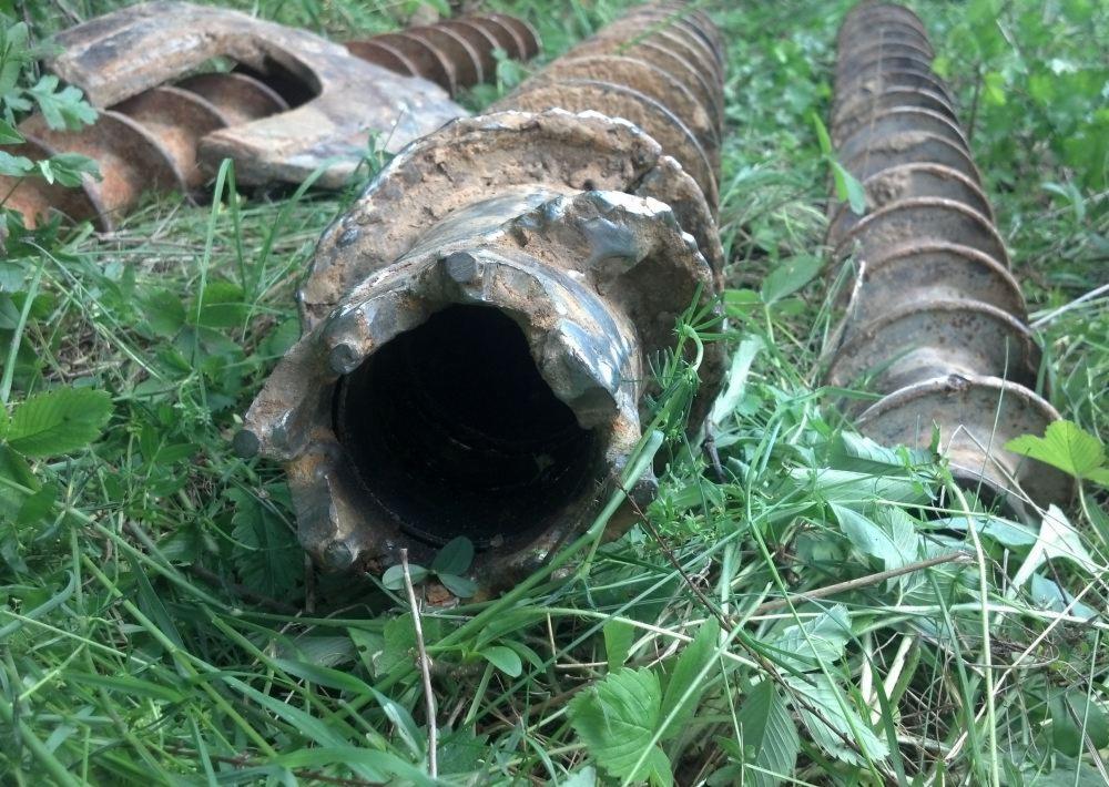 Wiertła geologiczne w trawie, Wieliczka. Widok z bliska na wiertło z zębami. Sprzęt do wierceń geologicznych w terenie.