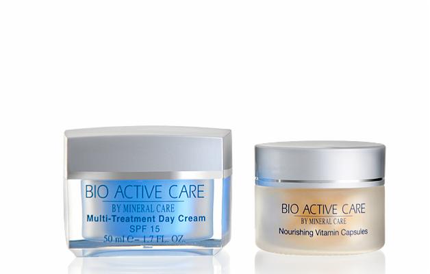 Dwa słoiczki kosmetyków Bio Active Care: krem na dzień SPF 15 i kapsułki witaminowe. Opakowania z matowego szkła z srebrnymi nakrętkami na białym tle.