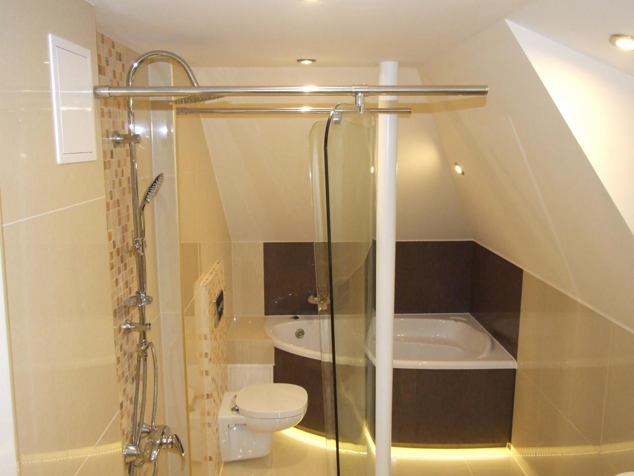 Nowoczesna łazienka na poddaszu z kabiną prysznicową typu walk-in, beżowymi płytkami i podświetlaną wanną. Uwagę zwraca nietypowy kształt pomieszczenia.