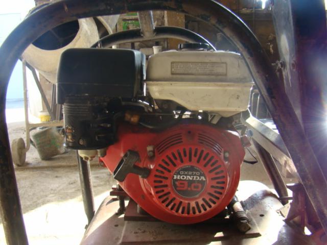 Silnik Honda GX270 9.0 zamontowany w zagęszczarce, widoczne elementy ramy ochronnej i betoniarka w tle.