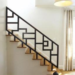 PW-POLMAR Sp. z o.o. - Nowoczesna, czarna poręcz schodowa z geometrycznym wzorem, drewniane stopnie, jasne wnętrze z lampą i zasłonami. Minimalistyczny design.