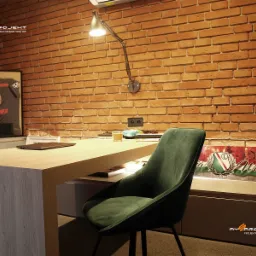 Biuro w stylu loft z ceglaną ścianą, drewnianym biurkiem, zielonym krzesłem i sportowymi akcentami - koszulka Lewandowskiego i flaga Legii Warszawa.
