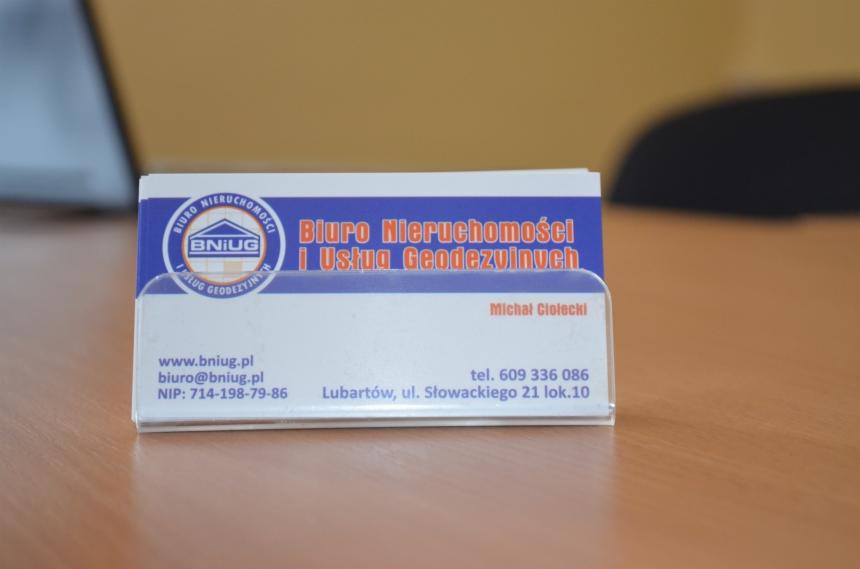 Wizytówka firmy BNIUG oferującej usługi geodezyjne i pośrednictwo w nieruchomościach. Na wizytówce logo, adres strony internetowej i numer telefonu.