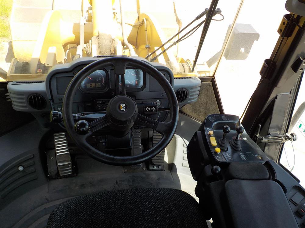Wnętrze kabiny maszyny budowlanej CAT 302.5C z widoczną kierownicą, deską rozdzielczą i dźwigniami sterującymi.