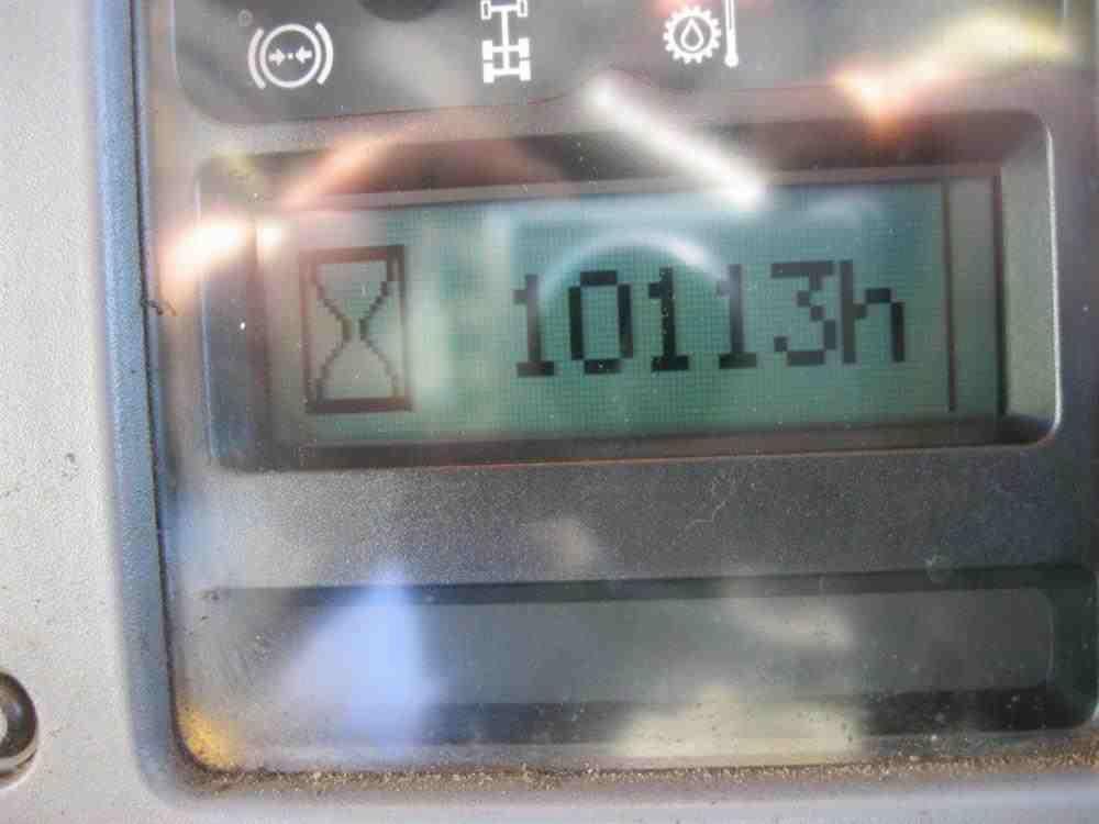 Wyświetlacz maszyny budowlanej pokazuje przepracowane 10113 godzin, widoczne ikony ostrzegawcze i kontrolne.