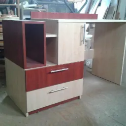 Biurko z szafką na wymiar z elementami w kolorze drewna wiśniowego, wykonane w Zawierciu, widoczne obrzeża meblowe w tle.