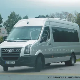 Srebrny bus Volkswagen Crafter z przyciemnianymi szybami, zaparkowany na placu, z anteną na dachu i widocznym numerem rejestracyjnym.