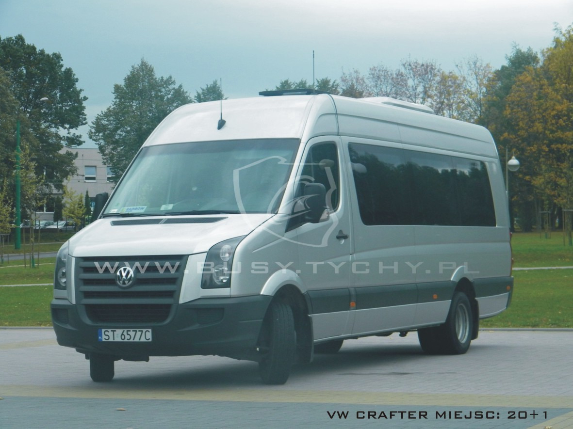 Srebrny bus Volkswagen Crafter z przyciemnianymi szybami, zaparkowany na placu, z anteną na dachu i widocznym numerem rejestracyjnym.
