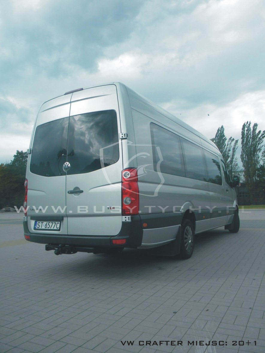 Srebrny bus VW Crafter z przyciemnianymi szybami, widok z tyłu na parkingu z kostki brukowej, hak holowniczy, tablica rejestracyjna ST 6577C.