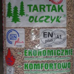 Worek przezroczysty z pelletem drzewnym, widoczne logo producenta 'Tartak Olczyk', certyfikaty DIN plus i EN A1 plus, oraz napisy 'Ekonomicznie', 'Komfortowo', 'Ekologicznie'.