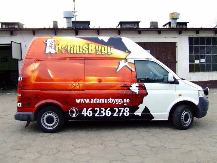 Samochód dostawczy z grafiką firmową: czerwono-biała kolorystyka, logo 'AdamusBygg', adres www i numer telefonu. Widok z boku na szarym tle.