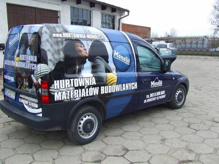 Oklejony samochód dostawczy z grafiką reklamową hurtowni materiałów budowlanych Monolit, z numerem telefonu i adresem strony internetowej.