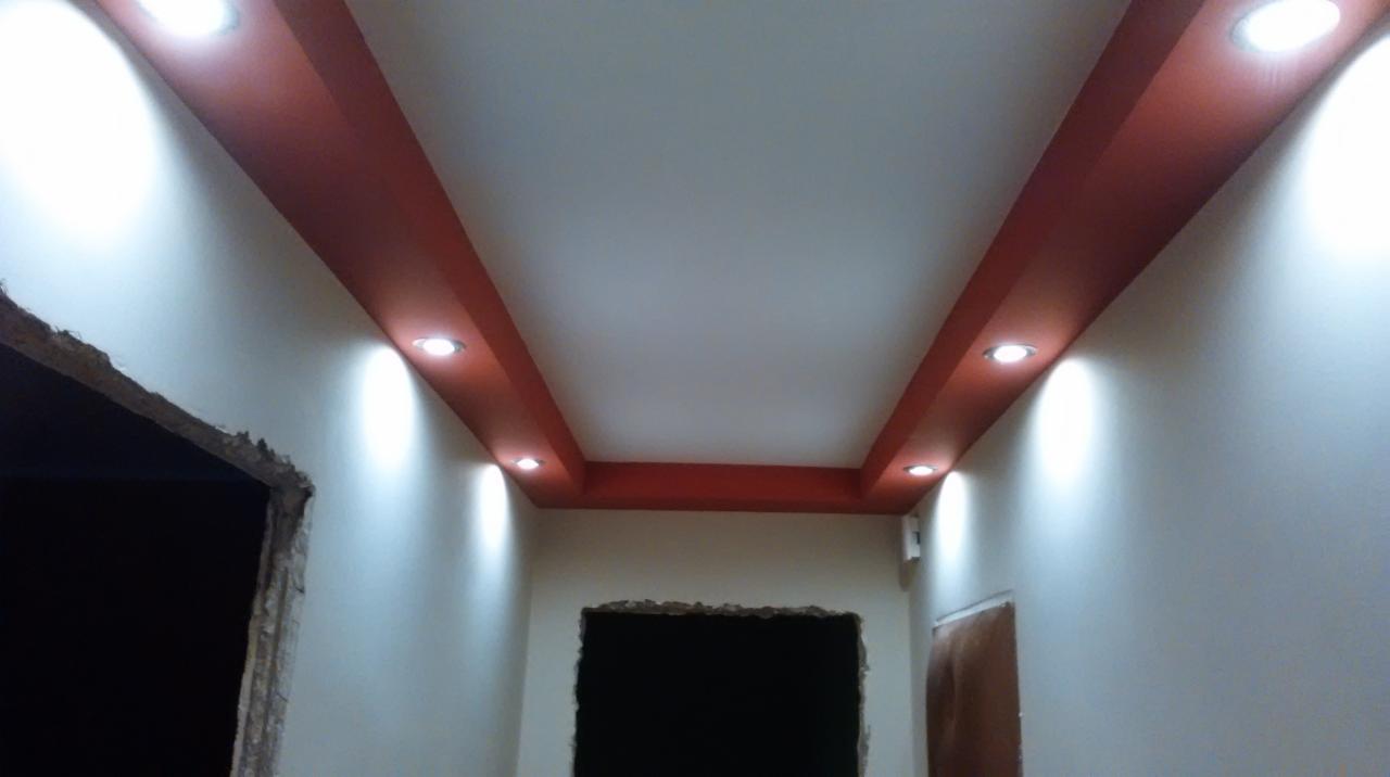Wykończony sufit z oświetleniem punktowym i czerwonymi elementami dekoracyjnymi w Radomiu. Widoczne przygotowane otwory na drzwi.