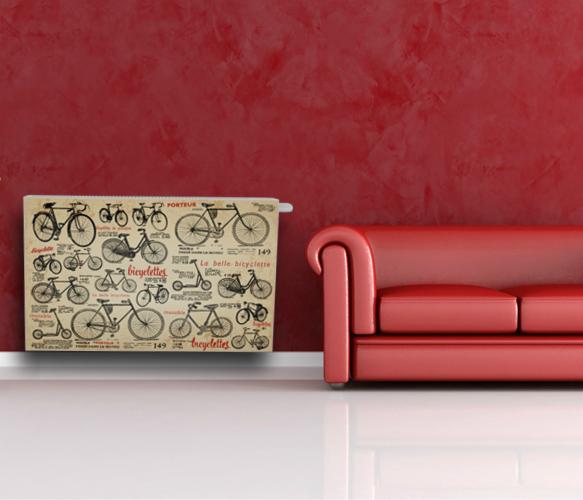 Grzejnik z dekoracyjnym panelem z motywem rowerów na tle czerwonej ściany i sofy. Nietypowe wykończenie grzejnika w aranżacji wnętrza.