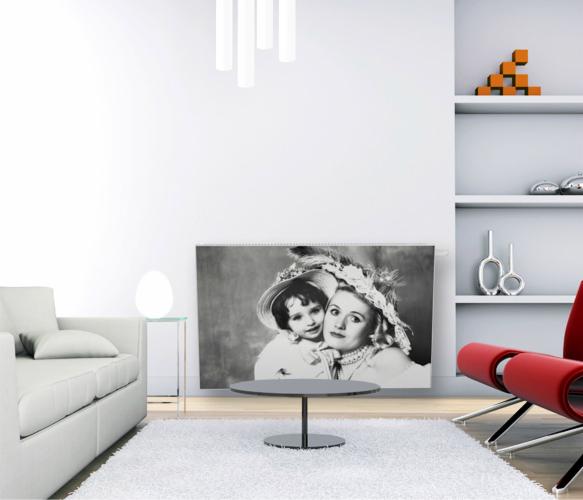 Białe wnętrze z grzejnikiem dekoracyjnym, na którym nadrukowano czarno-białe zdjęcie kobiety z dzieckiem. Nowoczesny design, minimalistyczny styl.