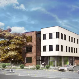 Wizualizacja budynku usługowego z elewacją z cegły i białych paneli, otoczonego zielenią i drzewami. Na pierwszym planie ulica z przechodniami i samochody.