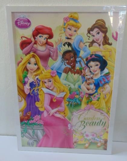 Oprawiony w białą ramę plakat z wizerunkami księżniczek Disneya: Ariel, Kopciuszek, Bella, Tiana, Śnieżka i Aurora. Napis 'Garden of Beauty' w dolnej części.