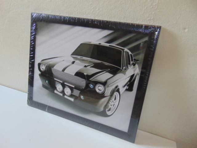 Oprawiony w ramę, czarno-biały plakat z wizerunkiem klasycznego, czarnego samochodu Mustang z białymi pasami, ustawiony pod kątem na białym tle.